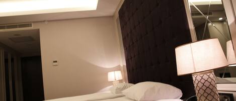 A hotel room with a bed, a bedside lamp, a telephone, and a mirror.
