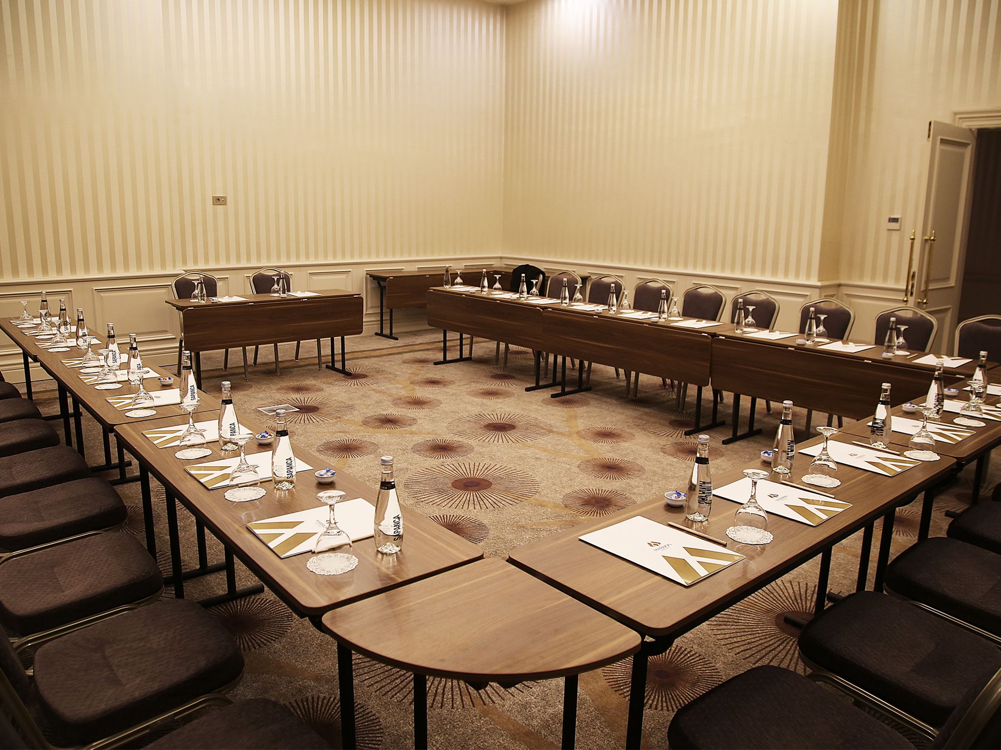 A conference room with long tables, chairs, and water bottles.