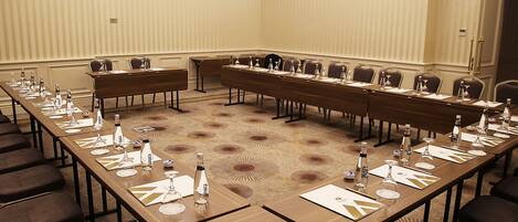 A conference room with long tables, chairs, and water bottles.