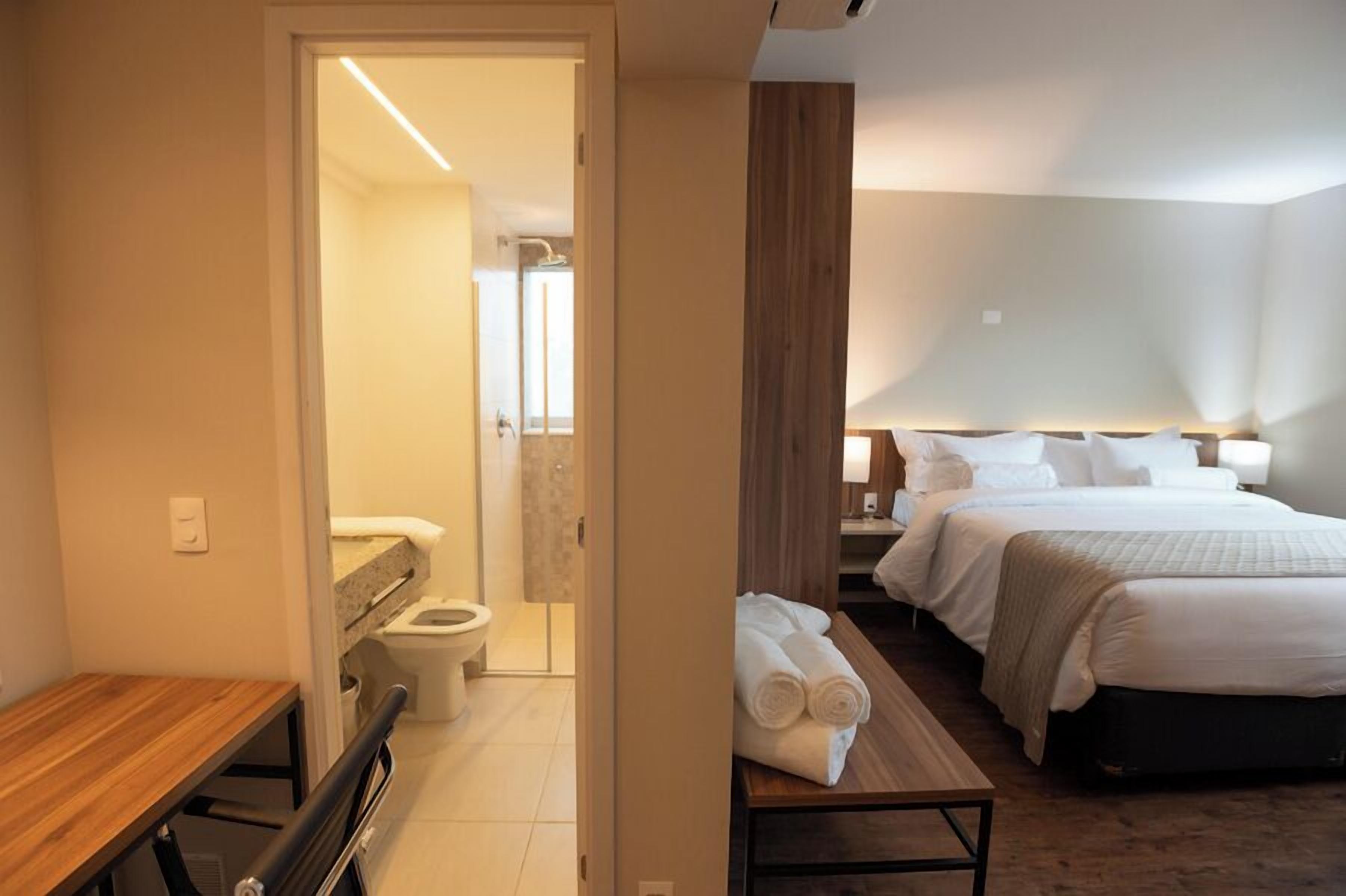 A hotel room with a bed, bedside table, and a view into the bathroom.