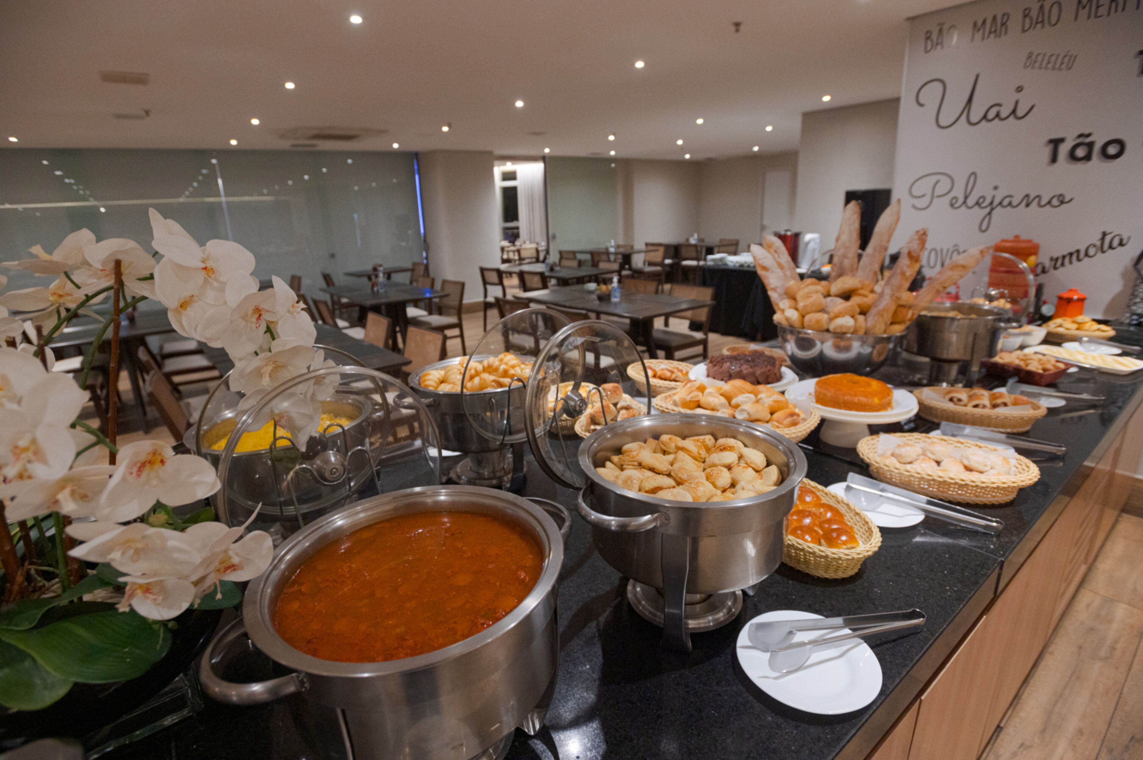 A buffet with various food items and a large sign with text in the background.