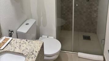 Et moderne badeværelse med en brusekabine i glas, toilet og håndvask med granitbordplade.