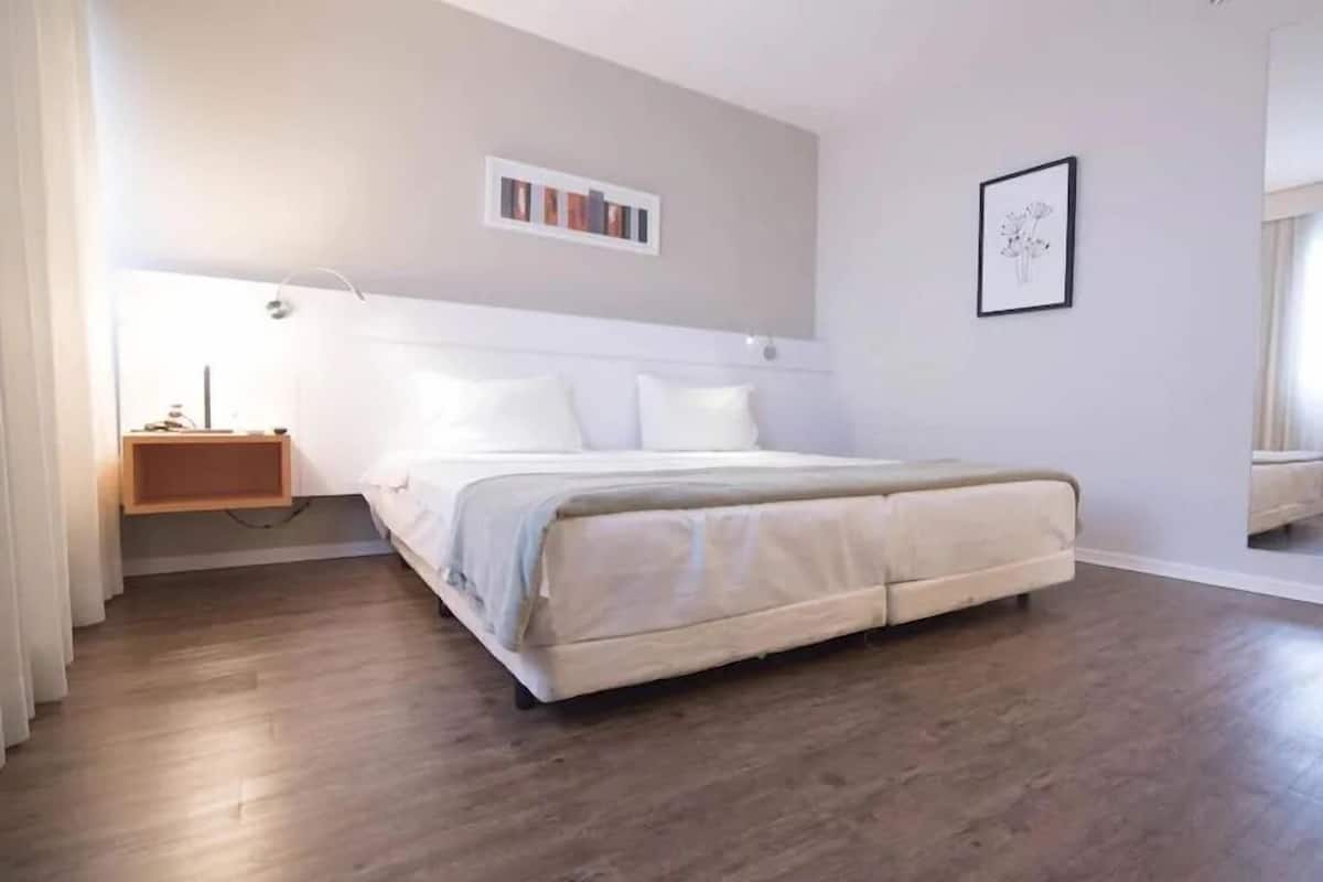 Un dormitorio con cama, mesita de noche y un cuadro colgado en la pared.