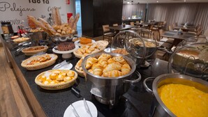 Un bufé con diversos alimentos, incluyendo pan, pasteles y una olla grande de sopa.