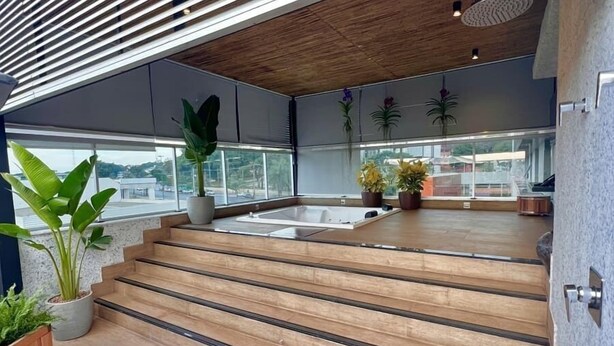 Un espacio exterior moderno con escalones de madera que conducen a una terraza, plantas en macetas y vistas a la ciudad.