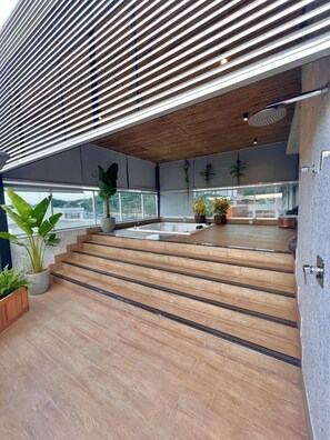 Un espacio exterior moderno con escalones de madera que conducen a una terraza, plantas en macetas y vistas a la ciudad.