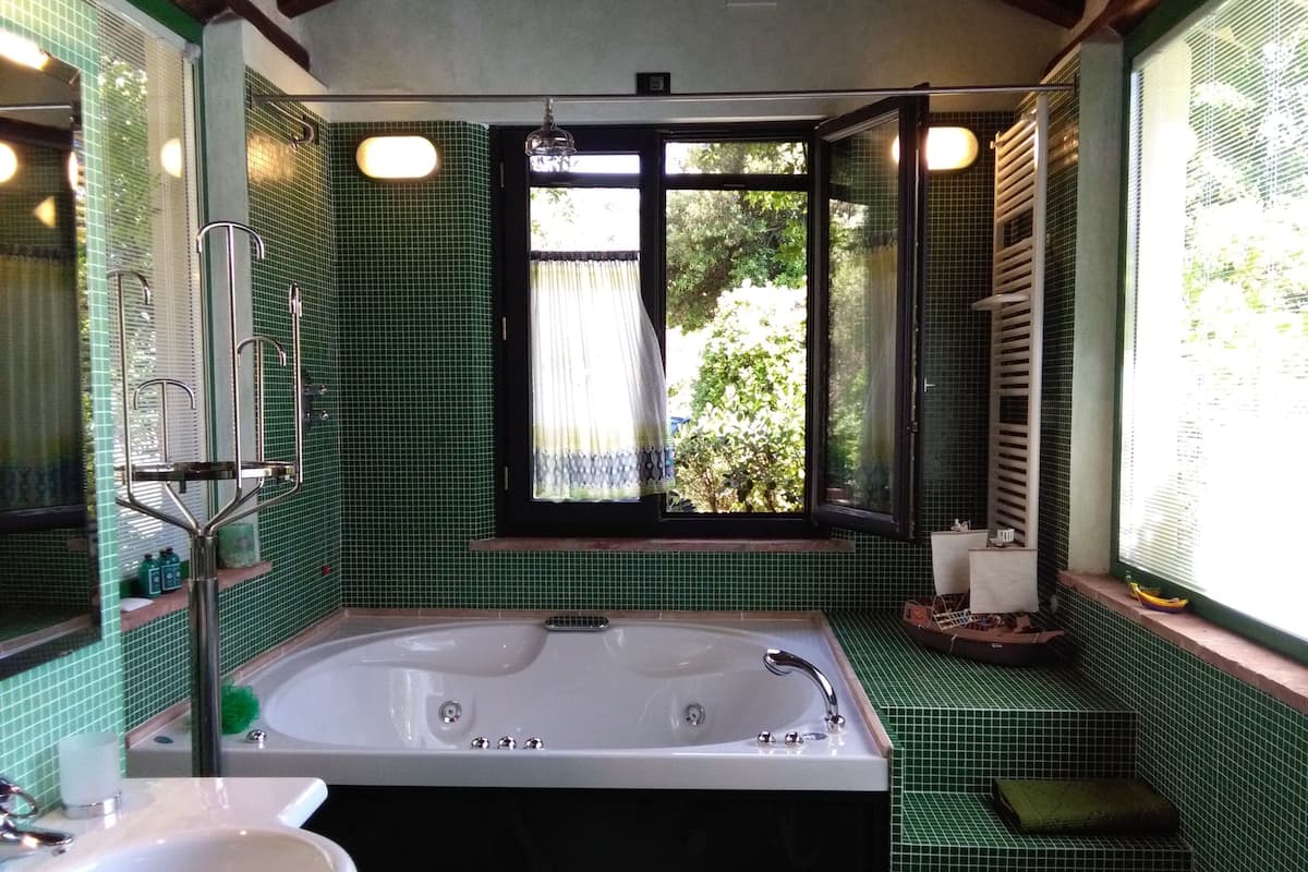 Ein Badezimmer mit einer großen Badewanne, einem Waschbecken und einem Fenster mit Vorhängen.