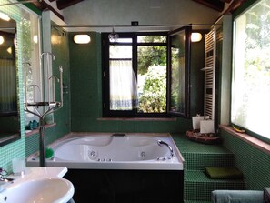 Une salle de bain avec une grande baignoire, un lavabo et une fenêtre avec des rideaux.