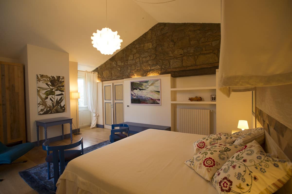 Ein Schlafzimmer mit Bett, Schreibtisch, Stuhl und einer Steinwand.