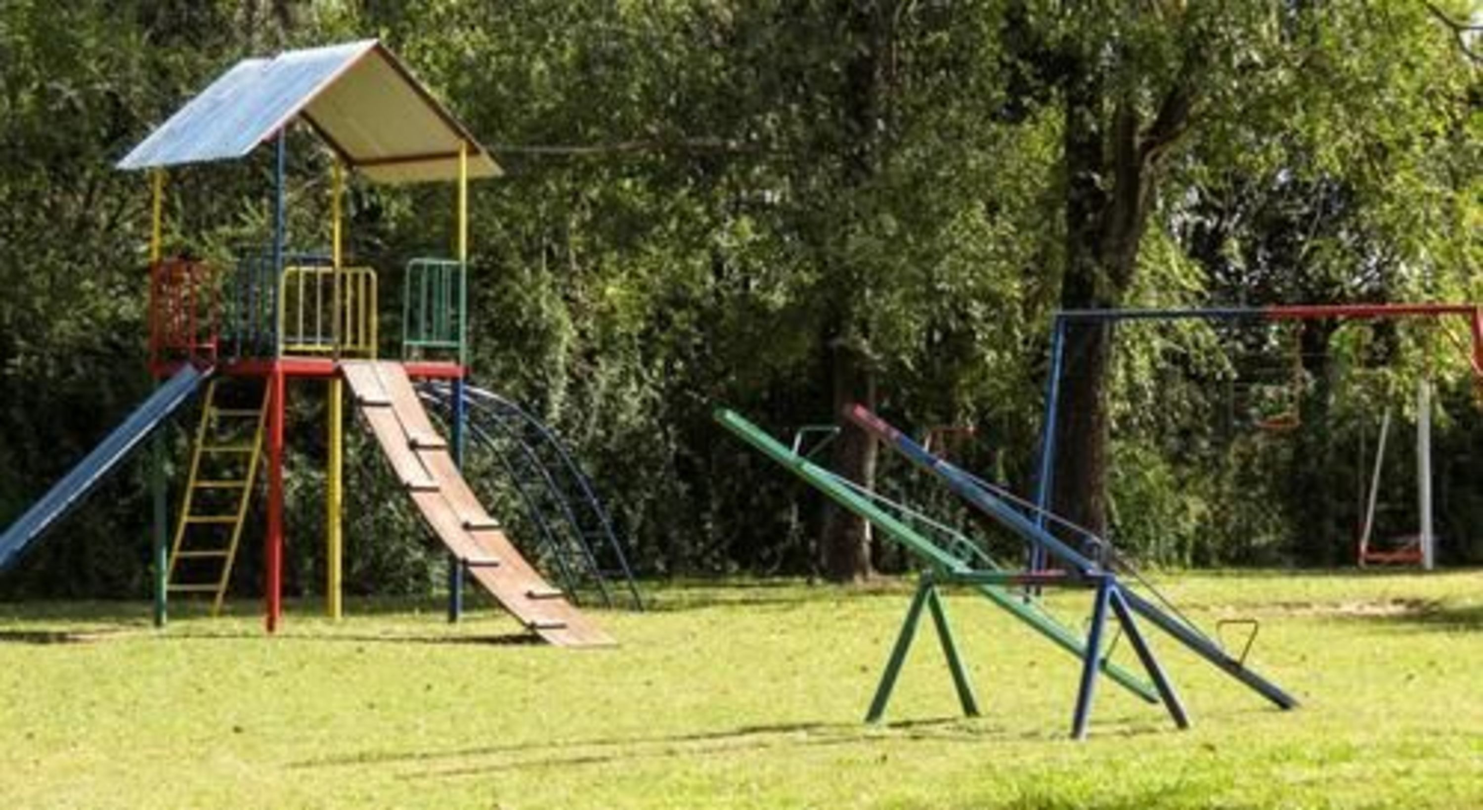 Un parque infantil con una estructura de escalada, toboganes y columpios.