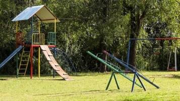 Un parque infantil con una estructura de escalada, toboganes y columpios.