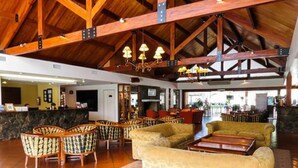 A spacious lobby with high ceilings, wooden beams, and a mix of seating including patterned chairs and sofas. - Howard Johnson by Wyndham, Villa General Belgrano (Villa General Belgrano)