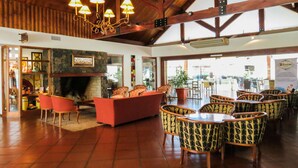 A spacious lobby with a fireplace, wooden ceiling beams, and a variety of seating arrangements. - Howard Johnson by Wyndham, Villa General Belgrano (Villa General Belgrano)