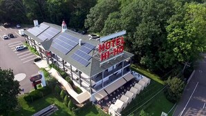 A hotel with a rooftop solar panel array, a covered outdoor seating area, and a parking lot.