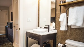 A bathroom with a white sink, dark vanity, and a towel rack.