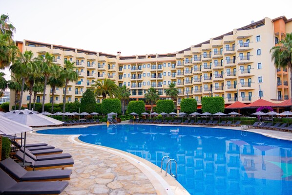 A hotel with a swimming pool, sun loungers, and palm trees. - Miramare Queen Hotel - All Inclusive (Manavgat)