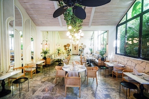 A restaurant with round tables, wicker chairs, and a stone accent wall. - Miramare Queen Hotel - All Inclusive (Manavgat)