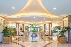 A spacious lobby with a central coffee table, seating area, and potted plants. - Miramare Queen Hotel - All Inclusive (Manavgat)