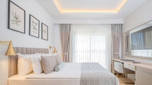 Ein Hotelzimmer mit Bett, Schreibtisch und großem Fenster mit Vorhängen.