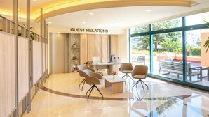Eine moderne Lobby mit Empfangsschalter, Sitzgelegenheiten und großen Fenstern mit Blick ins Freie.