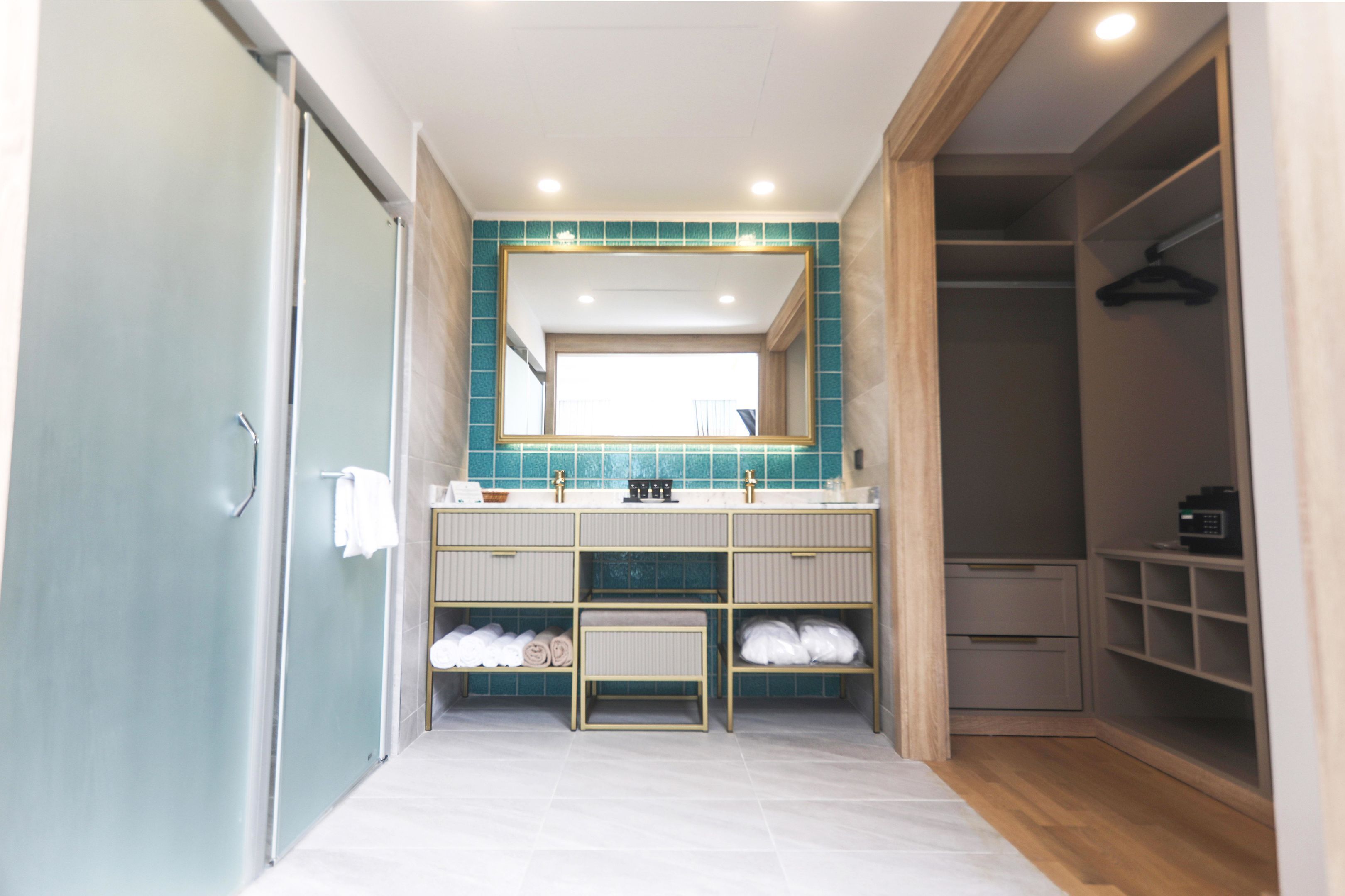 Un baño moderno con un espejo grande, lavamanos dobles y un vestidor.