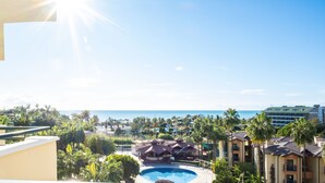 Ein Resort mit Pool, Palmen und Blick auf den Ozean.