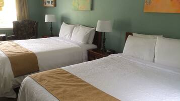 A hotel room with two beds, each with white linens and a brown throw blanket. There are two bedside tables with lamps, a chair, and a painting on the wall.