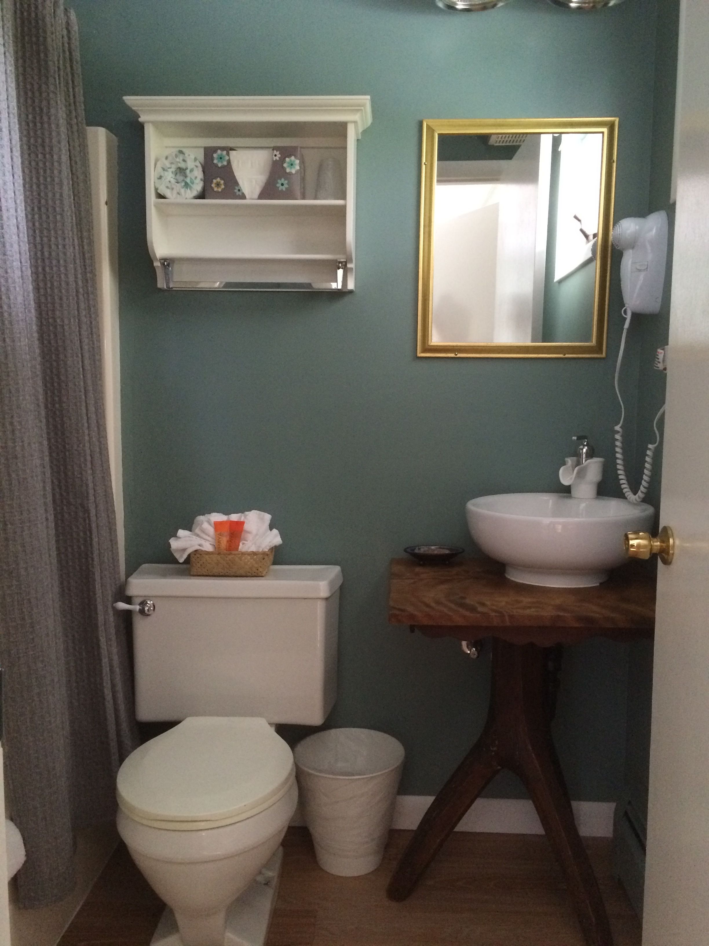Une salle de bain comprenant des toilettes, un lavabo, une poubelle, un miroir et un porte-serviettes.