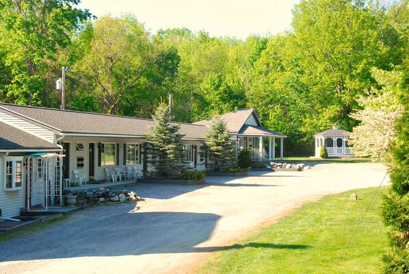 A lodge with a gravel driveway, a covered porch, and a small gazebo. - Harwood Hill Motel (Bennington)