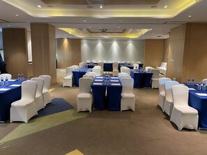 A conference room with rows of tables and chairs, equipped with water bottles and documents.
