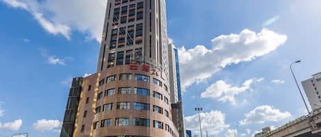 A multi-story hotel with a prominent entrance, large windows, and a clear sky.