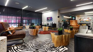 A modern lounge area with leather sofas, wooden coffee tables, and a zebra-patterned rug. - NYX Tel Aviv (Tel Aviv)