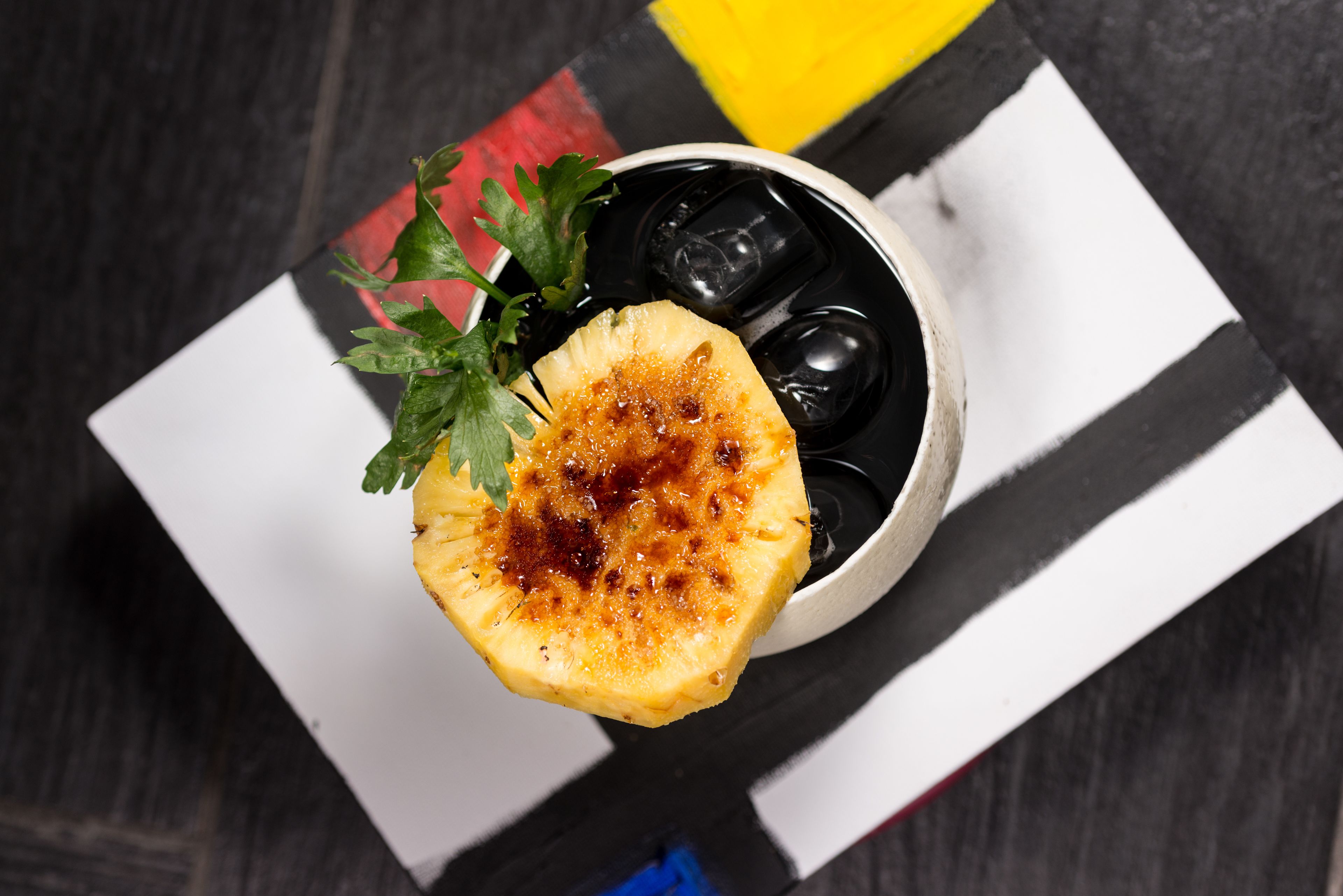 A pineapple slice with caramel sauce on a black and white striped cloth.