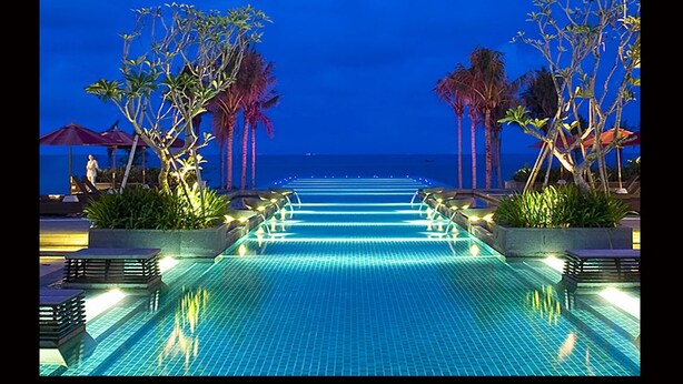 Una piscina infinita con vistas al océano al anochecer.
