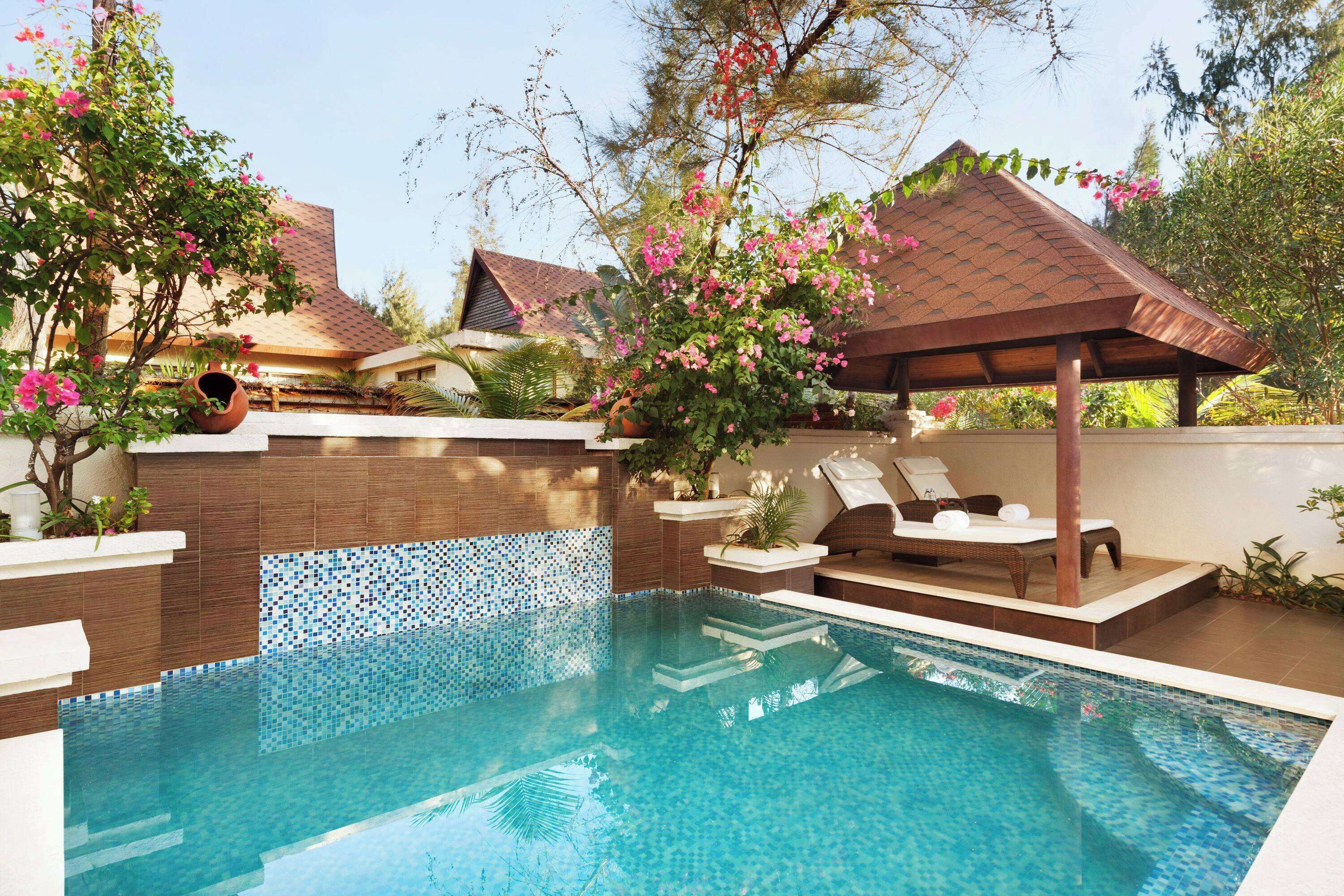 Una piscina con escalones de cerámica, sillas de descanso y una pérgola.