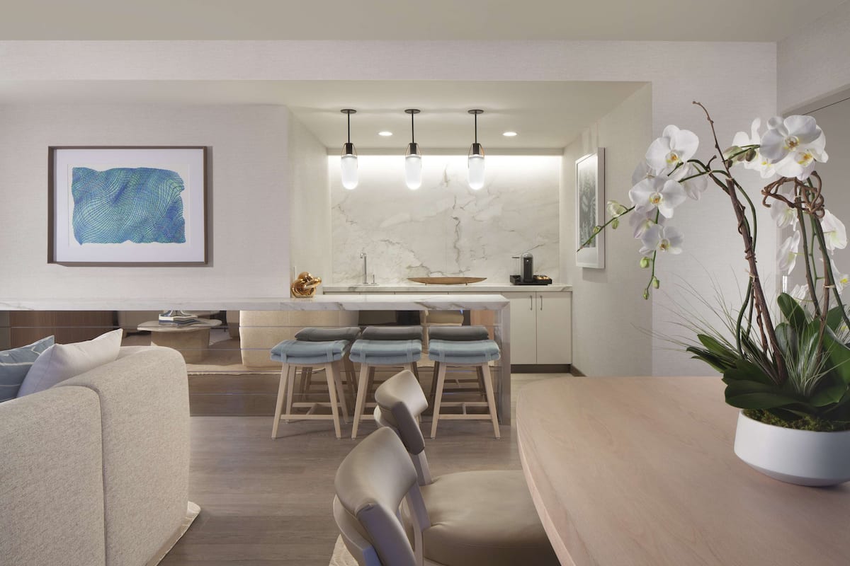Una cocina moderna con salpicadero de mármol, luces colgantes y una isla central con taburetes de bar.