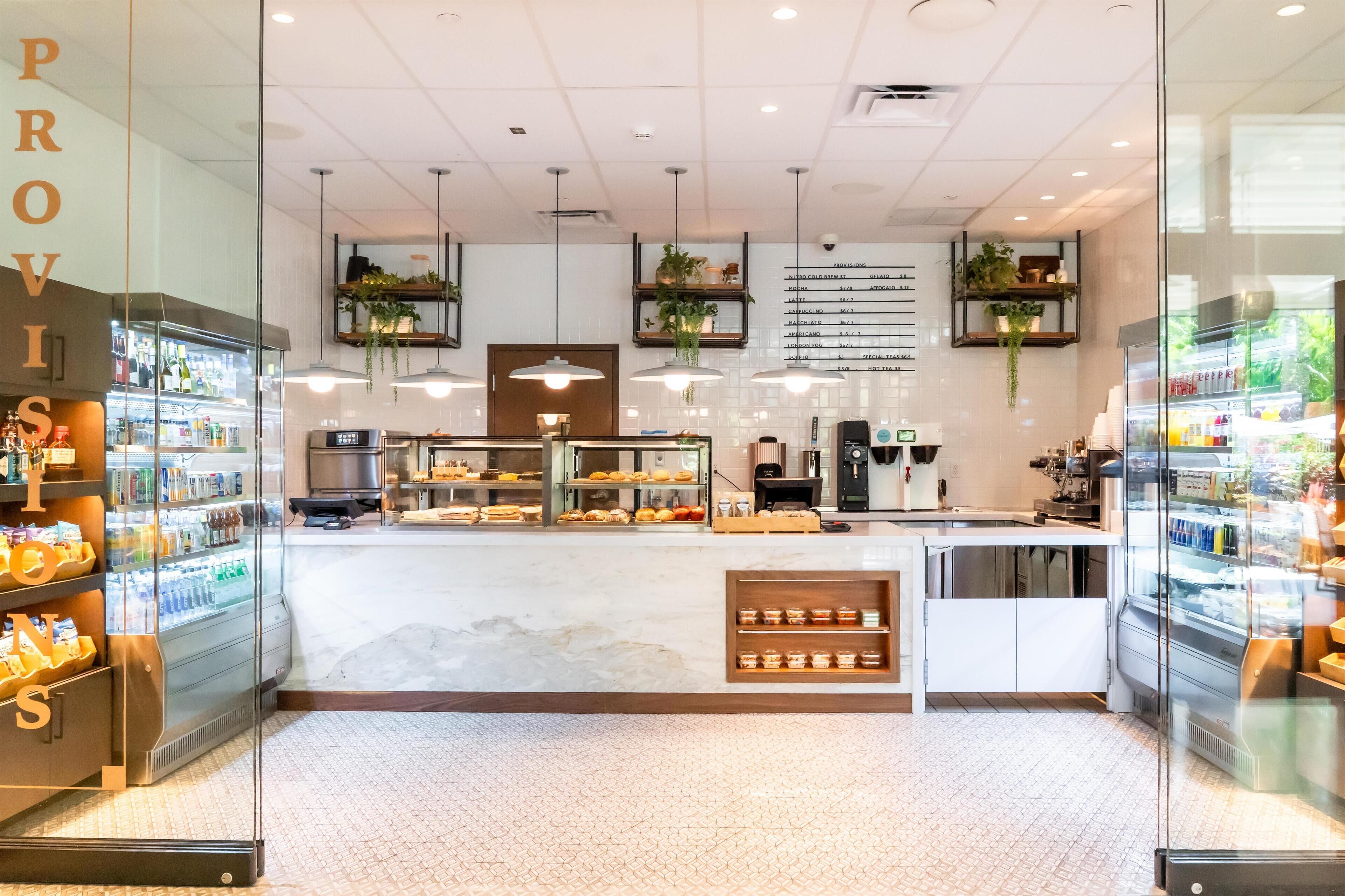 A cafe interior with a marble counter, hanging plants, and a menu on the wall.