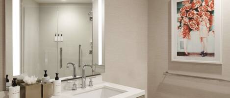 A modern bathroom with a large mirror, a sink, and a framed floral artwork on the wall.