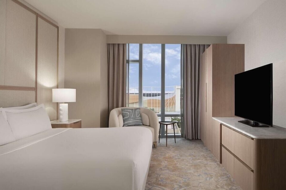 Une chambre d’hôtel avec un grand lit, un bureau doté d’un téléviseur à écran plat, une petite table et une chaise.