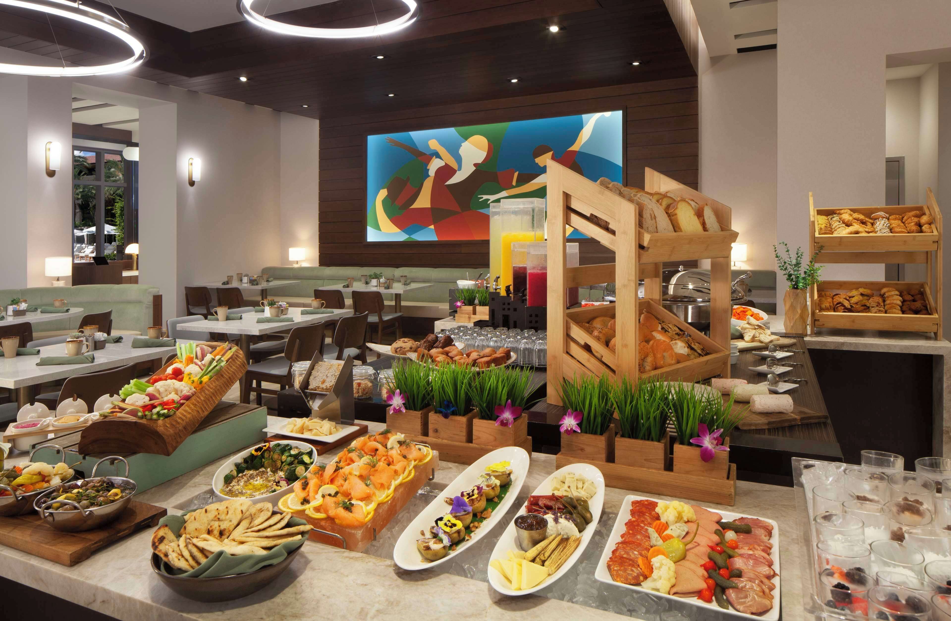 A buffet with various food items and a large screen displaying a colorful abstract painting.
