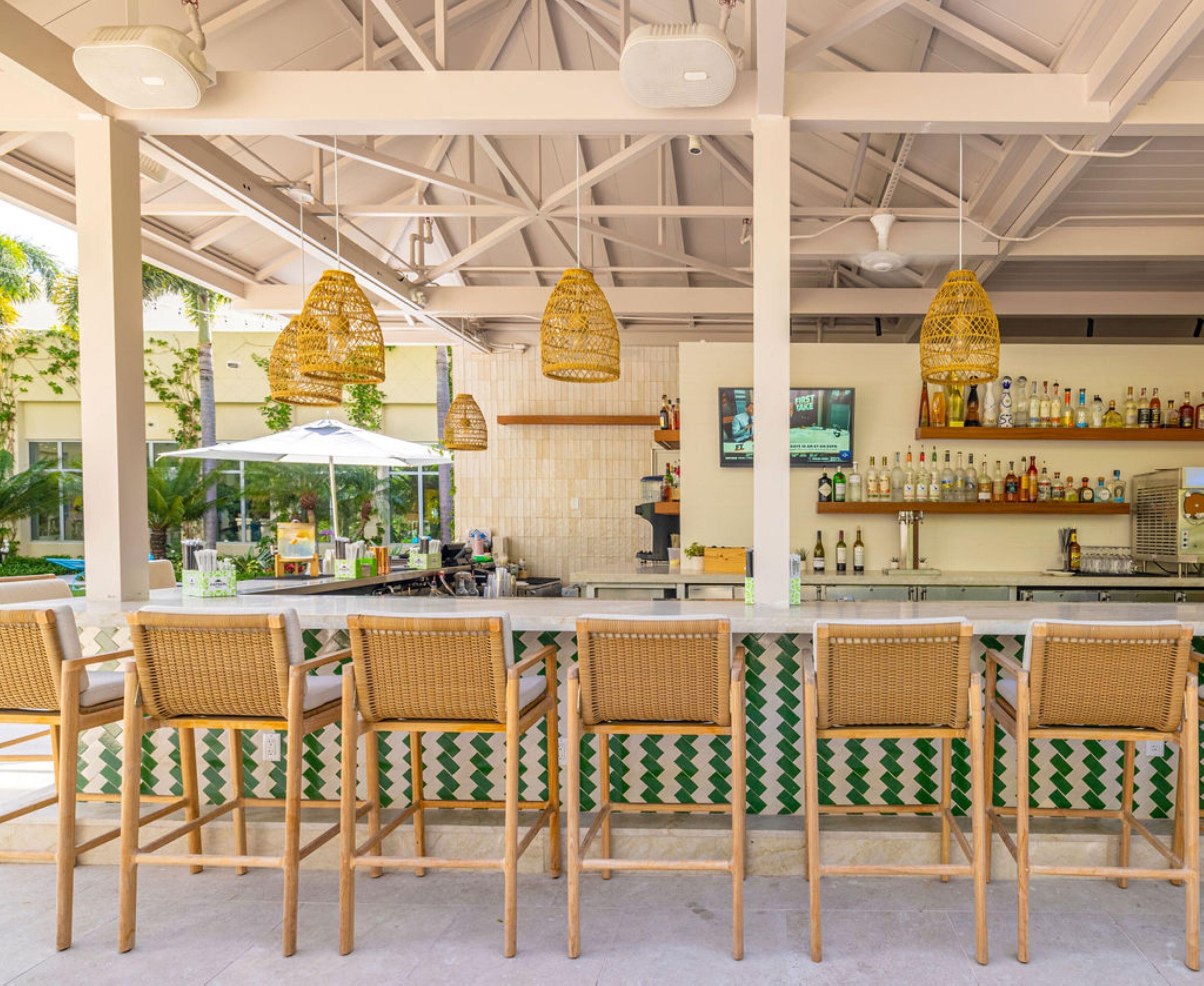 A bar area with wicker chairs, a counter with a TV, and a bar stocked with bottles.