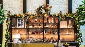 Zona de bar con estantes llenos de botellas de licores, un adorno festivo y una obra de arte enmarcada.