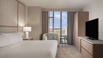 A hotel room with a large bed, a TV, a small table, and a chair.