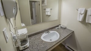 Un baño con lavamanos, espejo, toallero y secador de pelo.