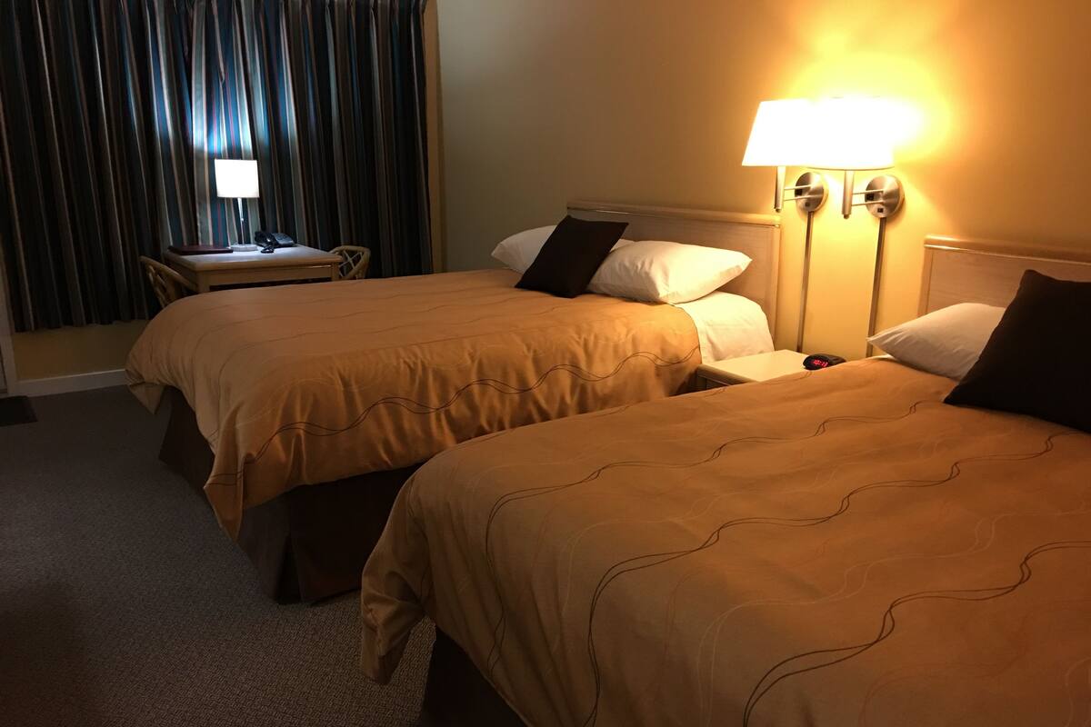 Een hotelkamer met twee bedden, een bureau en een lamp.