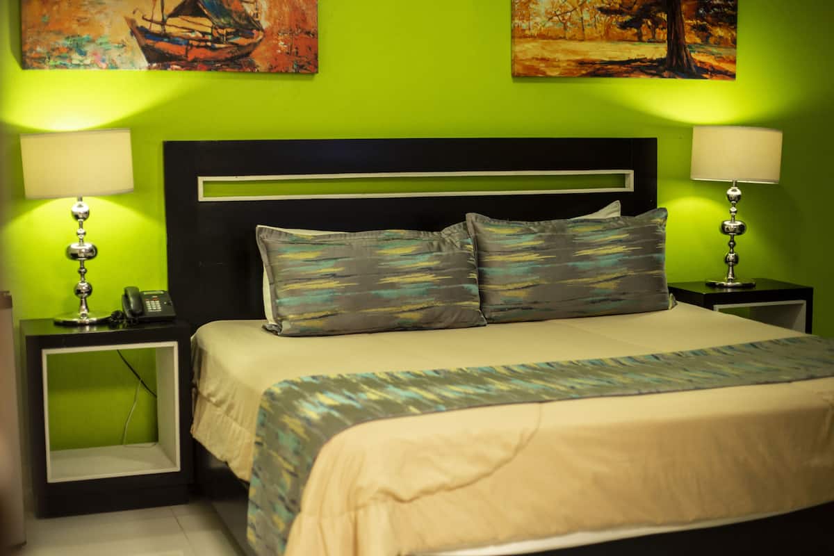 A bed with a headboard, two bedside tables with lamps, and artwork on the walls.