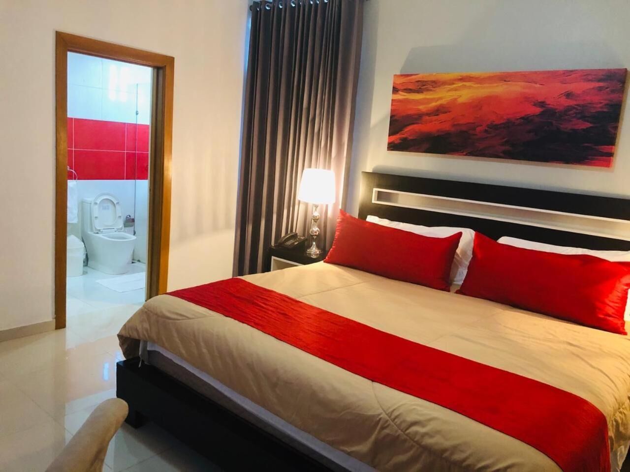 Ein Hotelzimmer mit Bett, einem Bild, einem Nachttisch und Blick ins Bad.