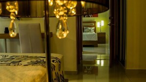 A hotel room with a bed, a chair, a nightstand, and a lamp. - Dpravia Hotel SRL (Bani)