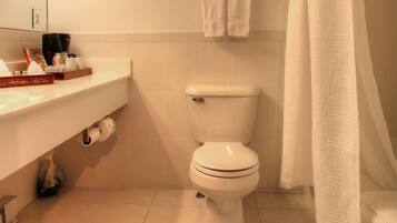 A bathroom with a toilet, a towel rack with towels, a shower curtain, and a sink with toiletries.