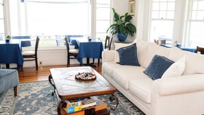 A well-lit living room with a white sofa, blue cushions, a coffee table with a decorative bowl, and a large potted plant. - Terrace by the Sea (Ogunquit)